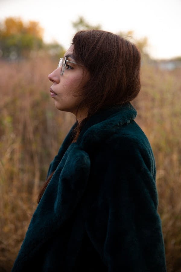 woman stands in field in profile