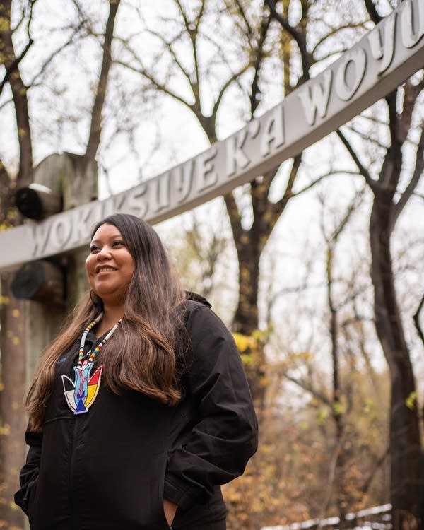 A woman standing under a sign. 