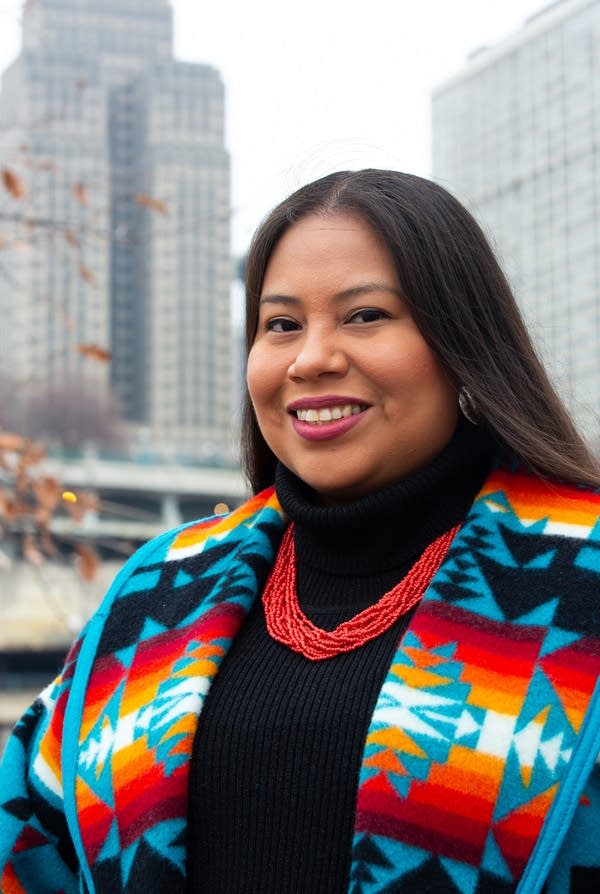 woman stands in front of buildings